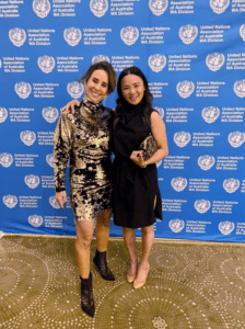 Photo of Dr. Katherine and another woman standing in front of a UN banner