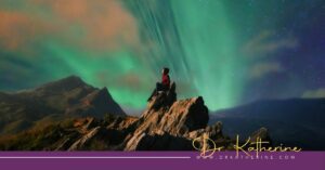 Photo of a woman sitting on a rack underneath the Northern Lights. A purple footer can be seen with the Dr. Katherine signature in yellow and www.drkatherine.com underneath that